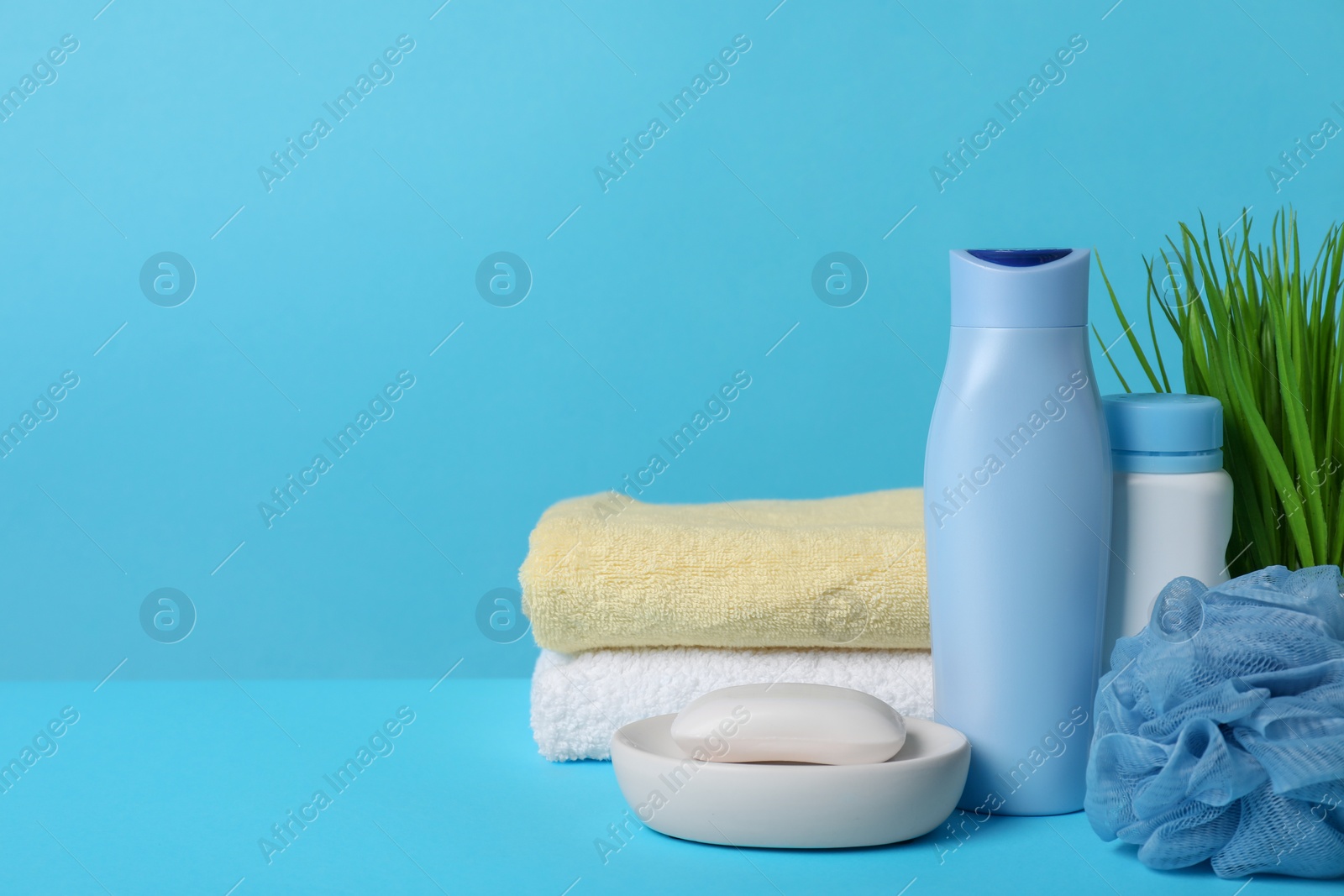 Photo of Baby cosmetic products, sponge and towels on light blue background. Space for text