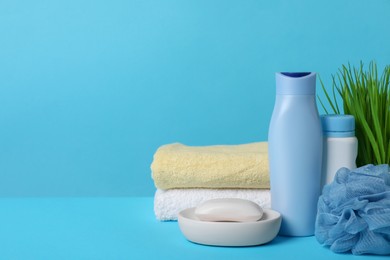 Photo of Baby cosmetic products, sponge and towels on light blue background. Space for text