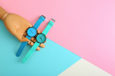 Wooden decorative hand and stylish wrist watches on color background, flat lay. Space for text