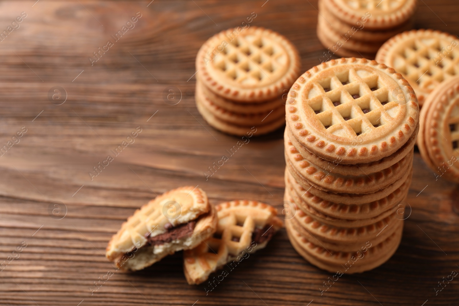 Photo of Tasty sandwich cookies with cream on wooden table, closeup. Space for text