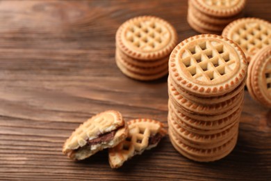 Tasty sandwich cookies with cream on wooden table, closeup. Space for text