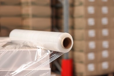 Photo of Roll of stretch wrap on box in warehouse, space for text
