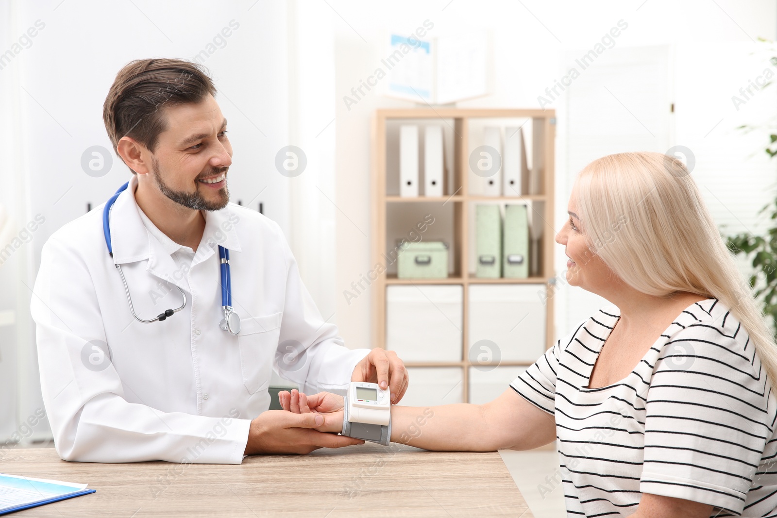 Photo of Doctor checking mature woman's pulse with medical device in hospital