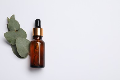 Photo of Aromatherapy product. Bottle of essential oil and eucalyptus leaves on white background, flat lay. Space for text
