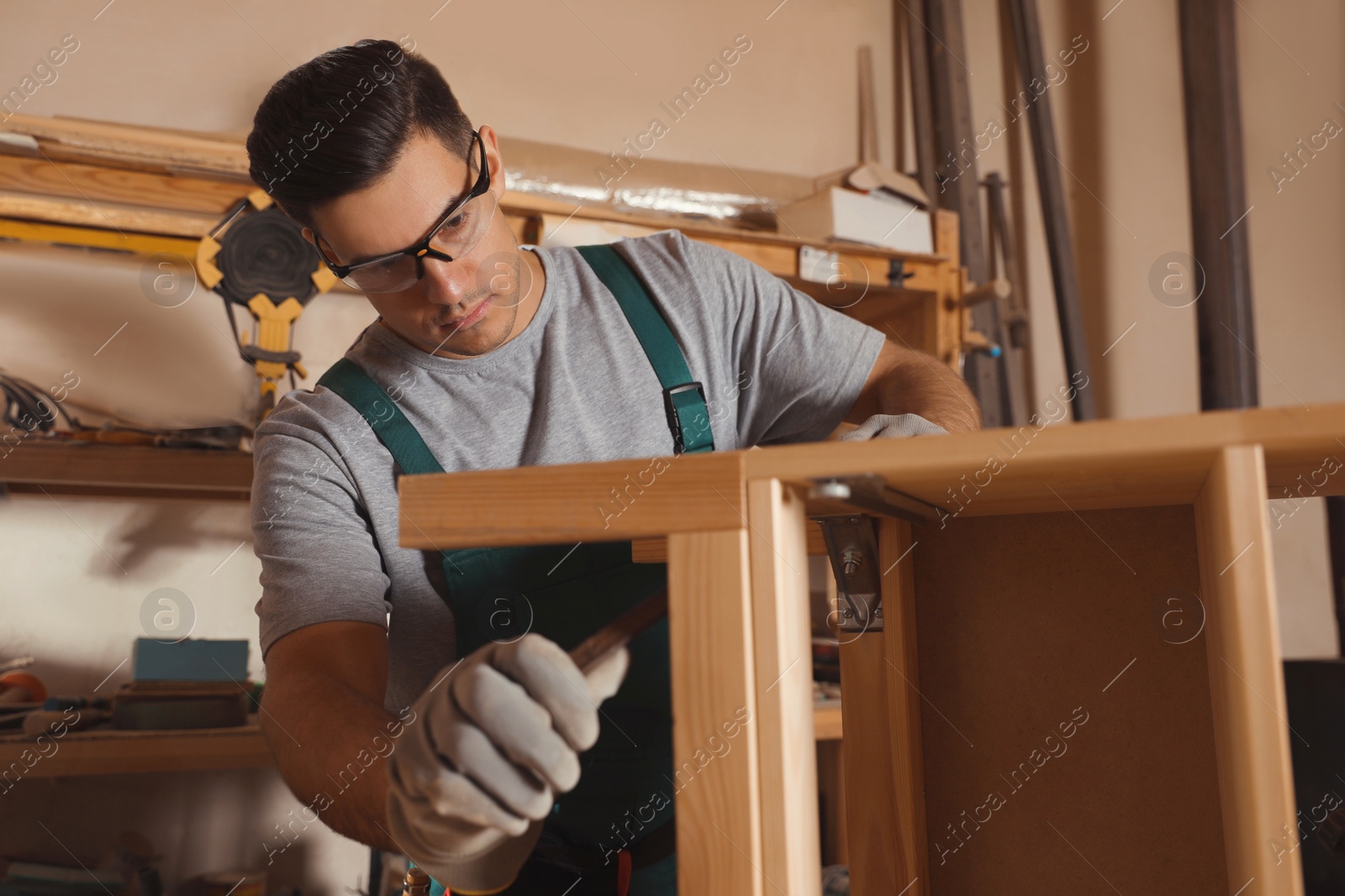 Photo of Professional carpenter assembling wooden cabinet in workshop