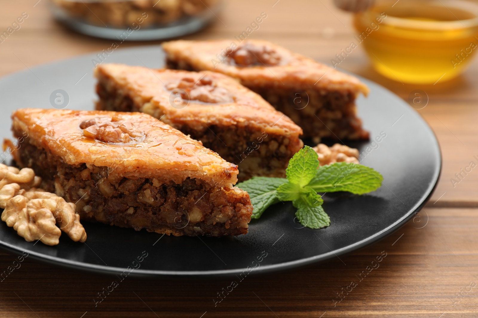 Photo of Delicious honey baklava with walnuts on wooden table, closeup