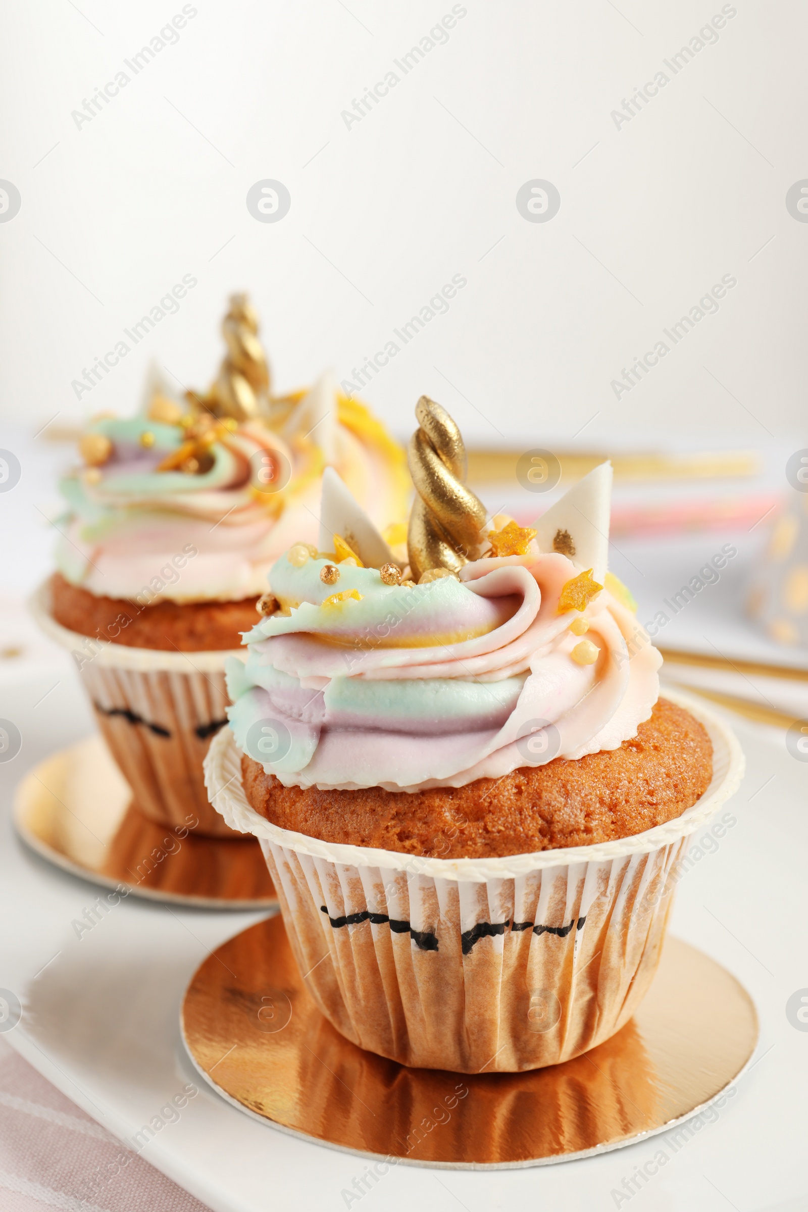 Photo of Cute sweet unicorn cupcakes on plate, closeup