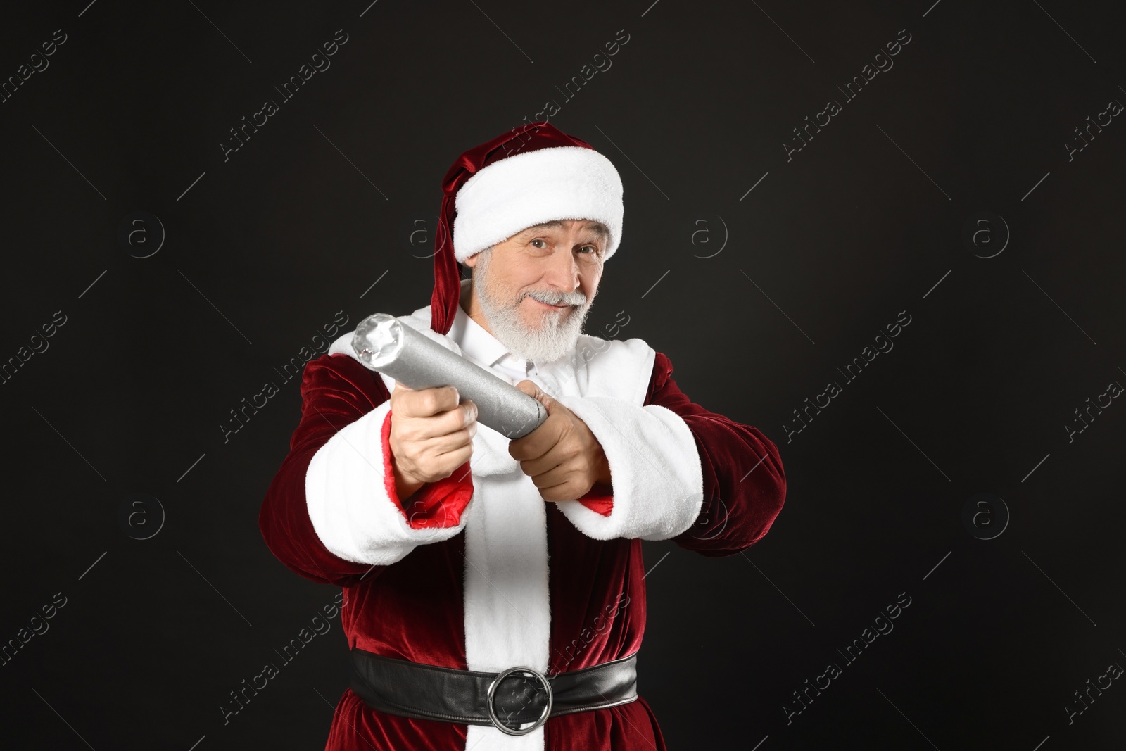 Photo of Man in Santa Claus costume with party popper on black background