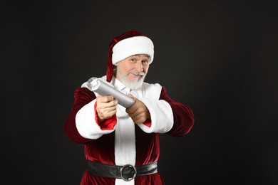 Photo of Man in Santa Claus costume with party popper on black background