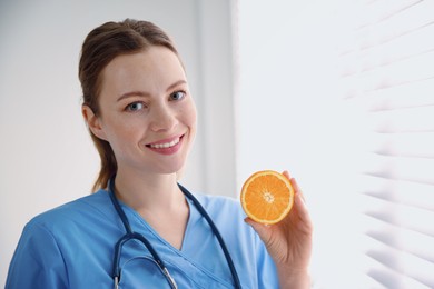 Nutritionist with orange near window in office