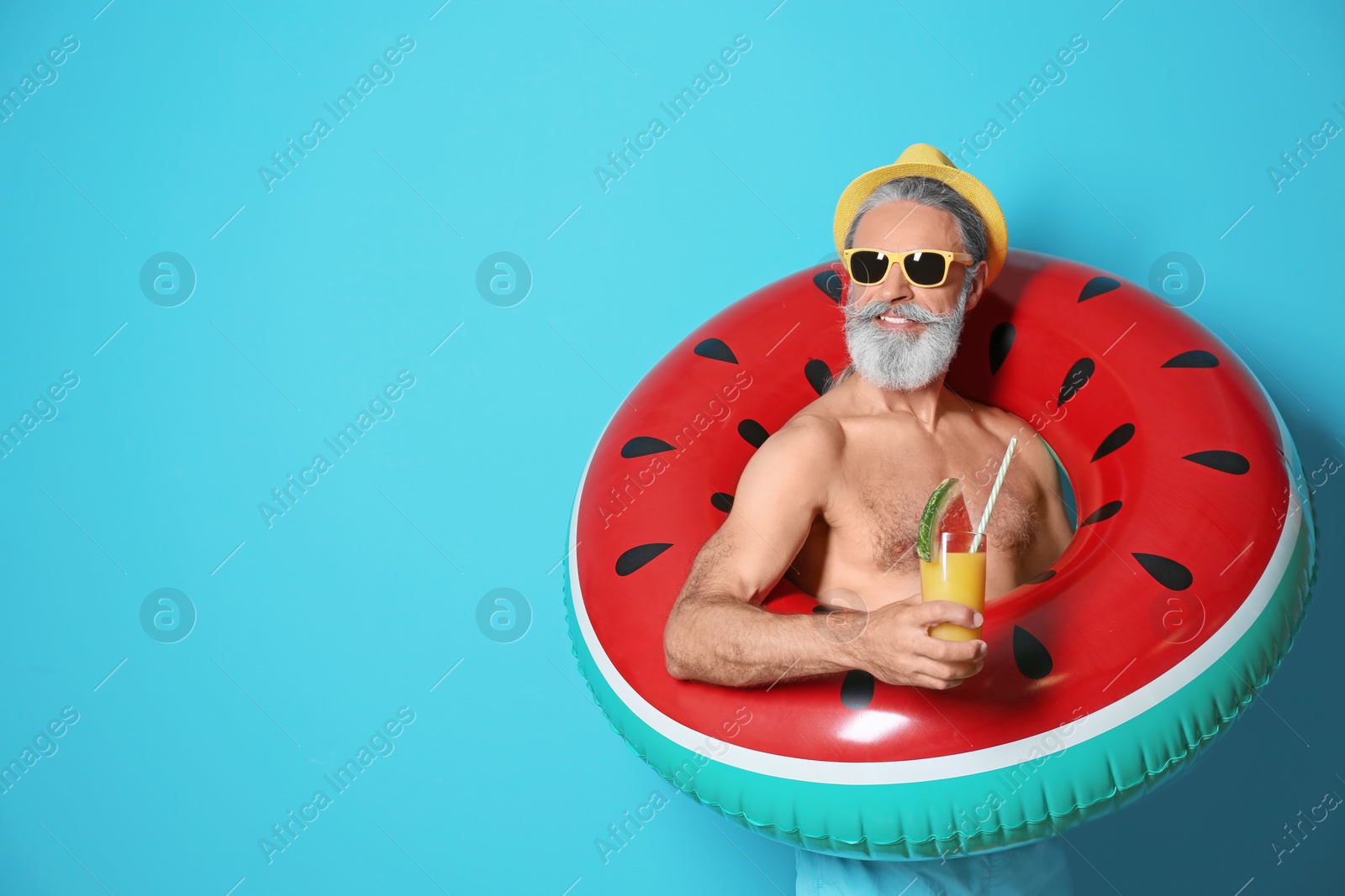 Photo of Shirtless man with inflatable ring and glass of cocktail on color background