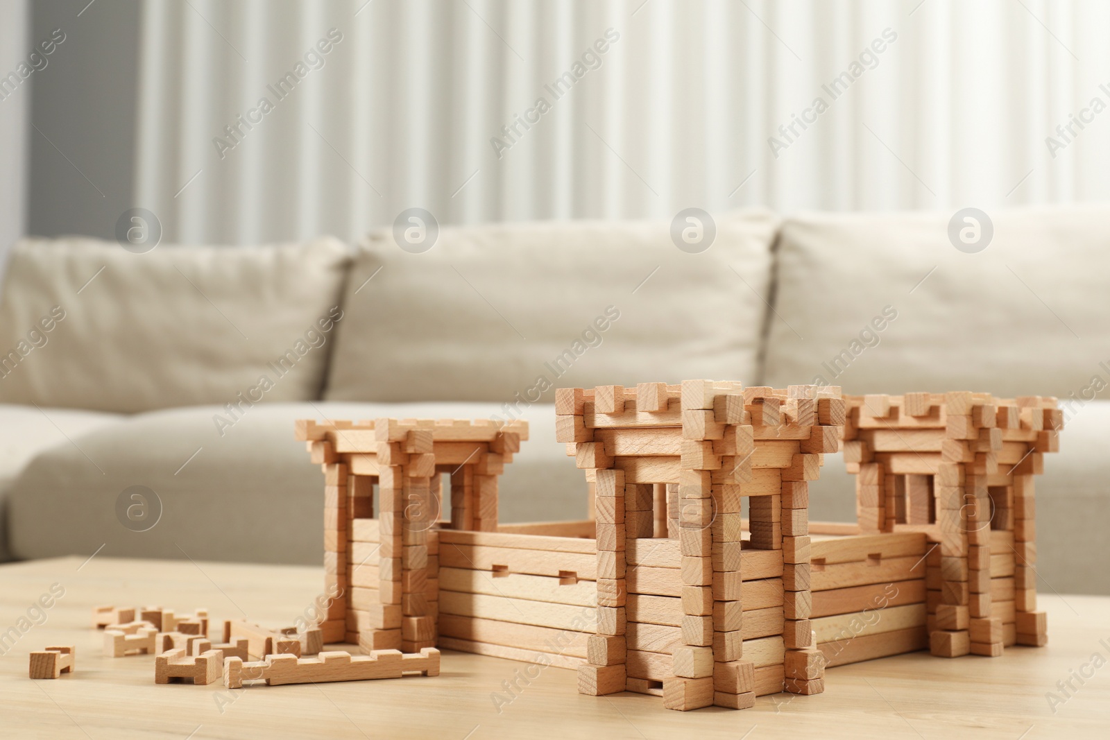 Photo of Wooden fortress and building blocks on table indoors. Children's toy