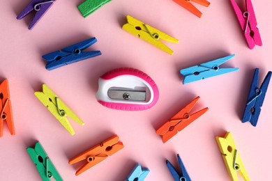 Photo of Colorful clothespins and sharpener on pink background, flat lay. Diversity concept