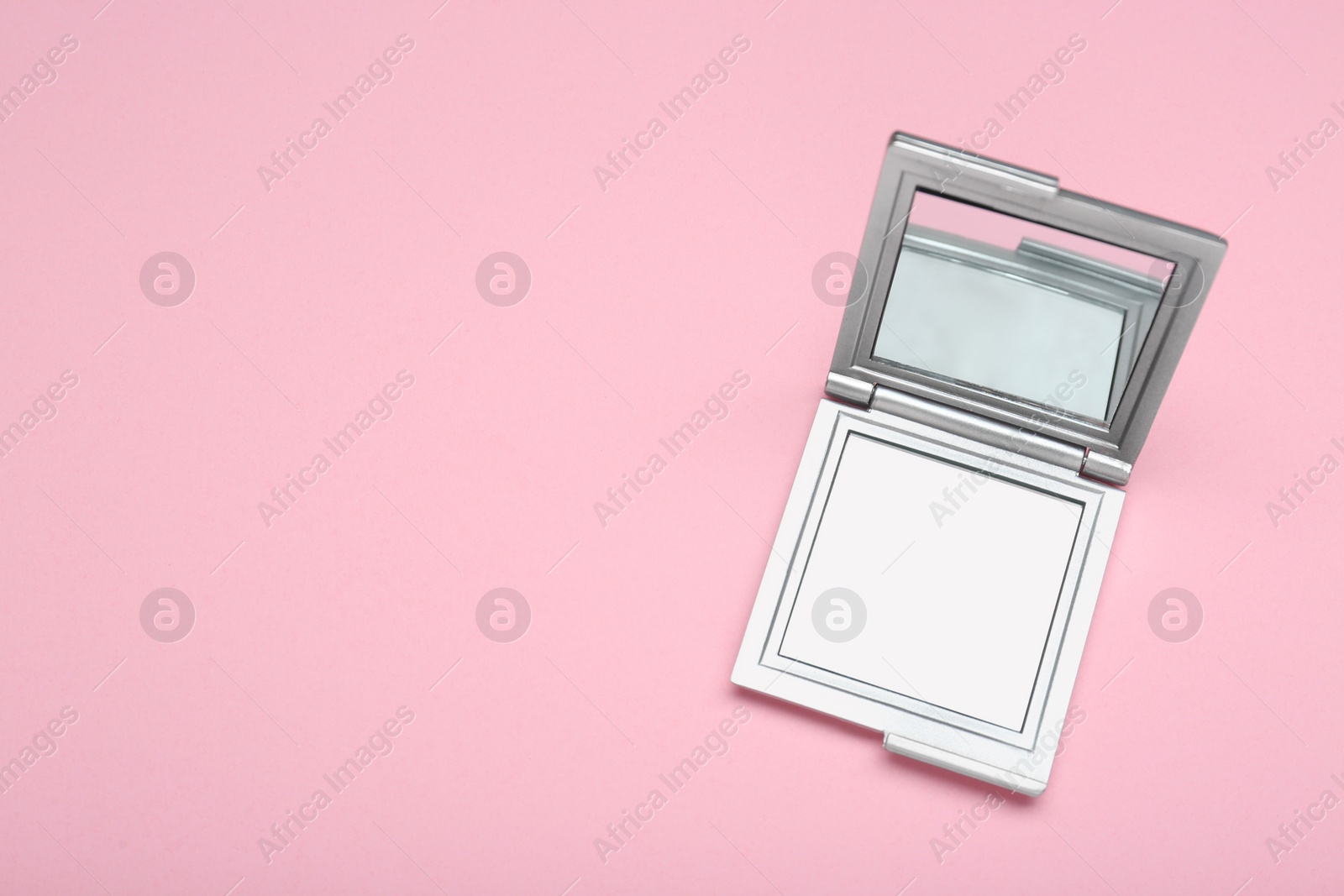 Photo of Stylish cosmetic pocket mirror on pink background, top view. Space for text