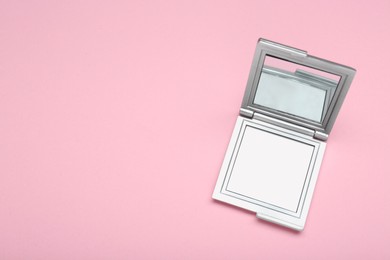 Stylish cosmetic pocket mirror on pink background, top view. Space for text