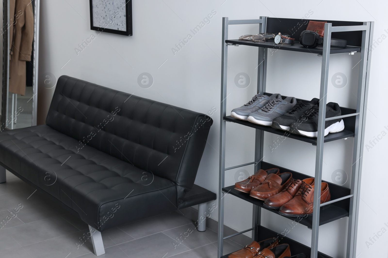 Photo of Stylish sofa and shoe storage unit near white wall in hallway. Interior design