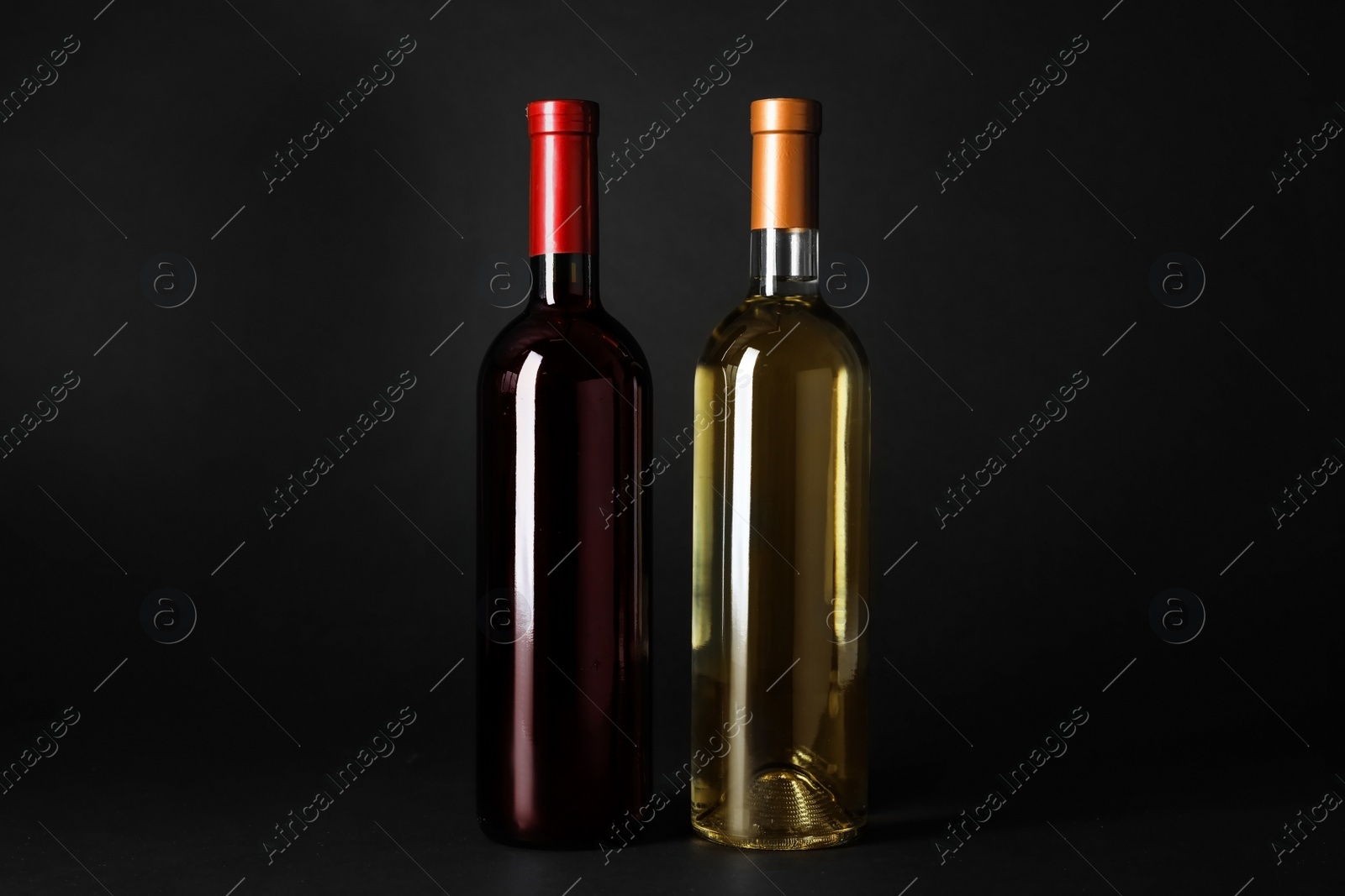 Photo of Bottles of expensive red and white wines on dark background