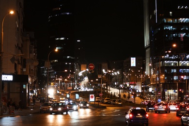 Photo of KYIV, UKRAINE - MAY 22, 2019: View of illuminated city street with road traffic and buildings