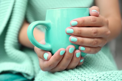 Photo of Young woman with stylish mint manicure holding cup, closeup