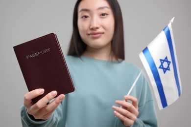 Immigration to Israel. Woman with passport and flag on grey background, selective focus