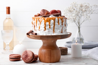 Delicious homemade cake with caramel sauce and cookies on table