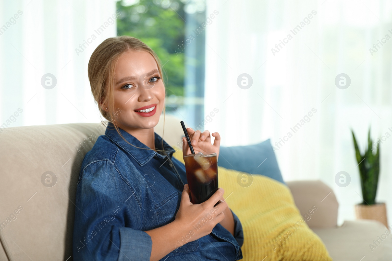 Photo of Young woman with glass of cola at home. Refreshing drink