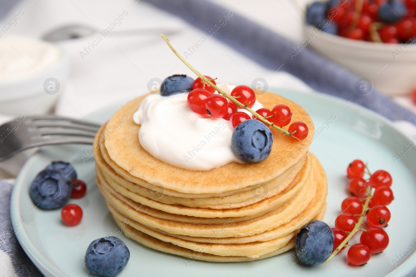Photo of Tasty pancakes with natural yogurt, blueberries and red currants on table, closeup