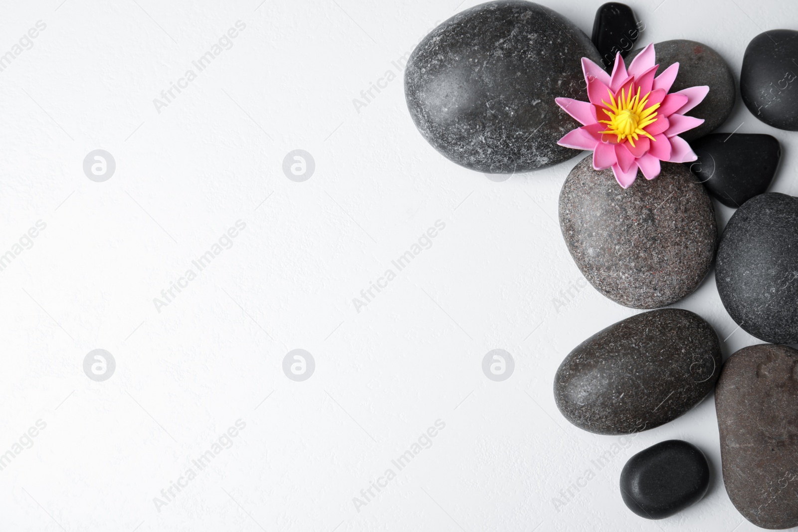 Photo of Stones with lotus flower and space for text on white background, flat lay. Zen lifestyle