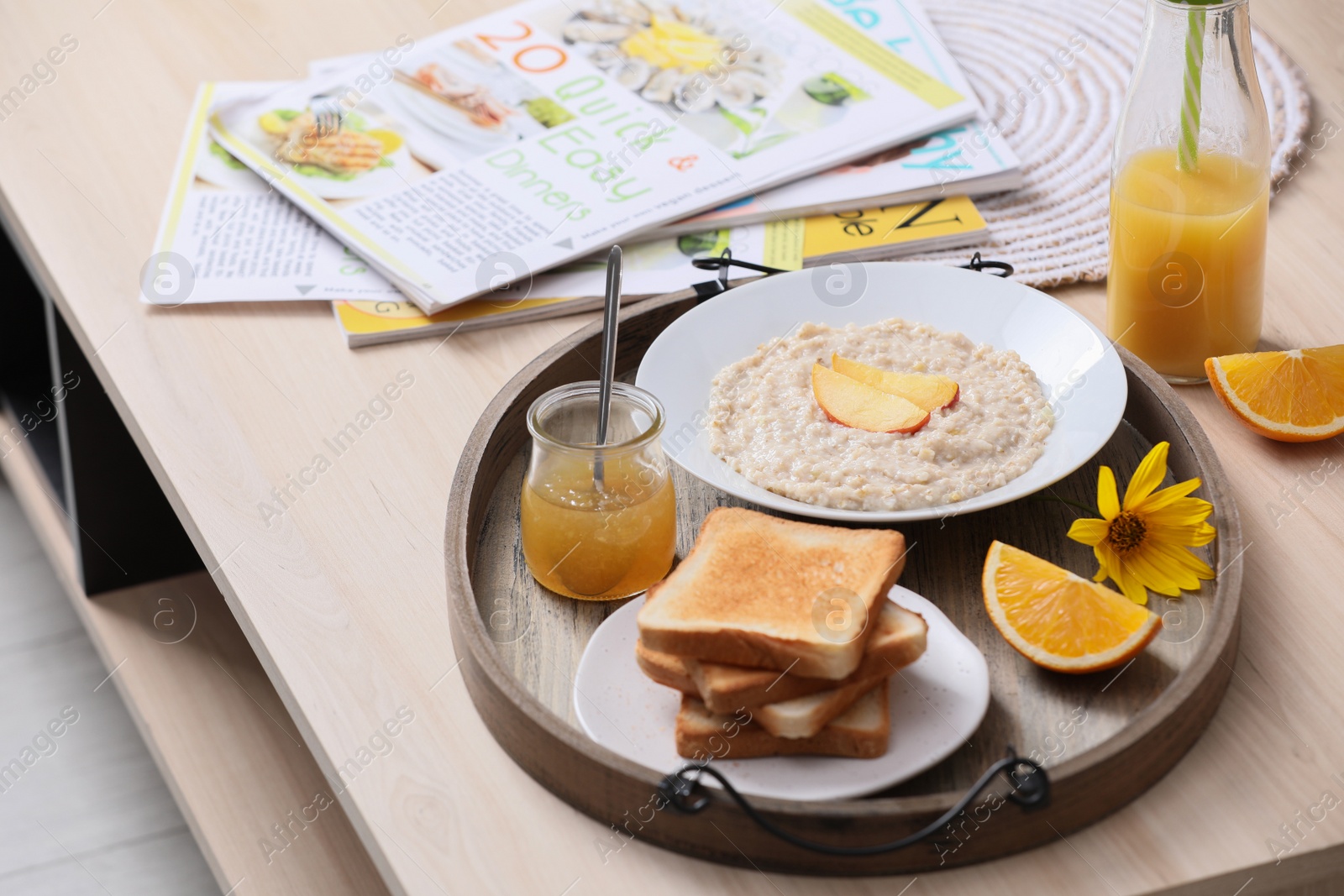 Photo of Wooden tray with delicious breakfast and beautiful flower on table