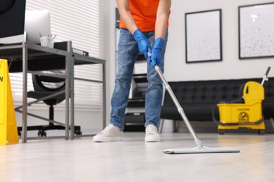 Photo of Cleaning service. Man washing floor with mop, closeup
