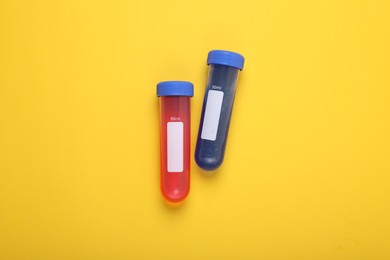 Photo of Test tubes with colorful liquids on yellow background, flat lay. Kids chemical experiment set