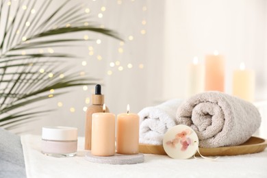 Photo of Spa composition. Burning candles and personal care products on soft surface