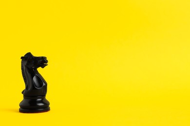 Photo of Black knight on yellow background, space for text. Chess piece