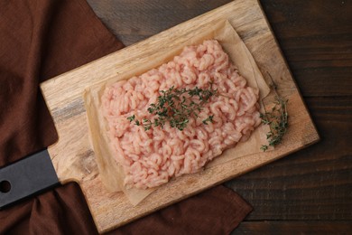 Photo of Fresh raw minced meat and thyme on wooden table, top view