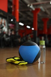 Photo of Medicine ball, bottle and weighting agents on floor in gym
