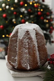 Photo of Traditional Italian pastry. Delicious Pandoro cake decorated with powdered sugar on white table in room