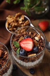 Photo of Tasty granola with berries, nuts and yogurt on table, closeup