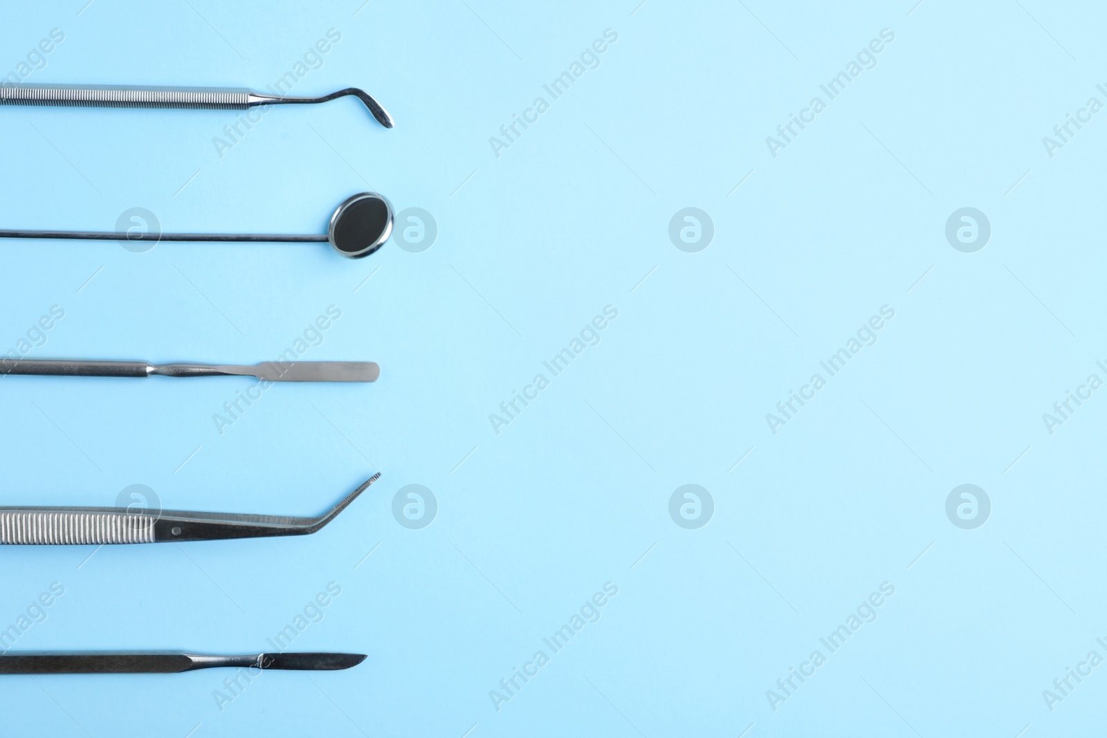 Photo of Set of dentist tools on color background, top view with space for text