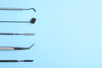 Photo of Set of dentist tools on color background, top view with space for text