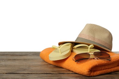 Photo of Beach towel, flip flops, hat and sunglasses on wooden surface against white background