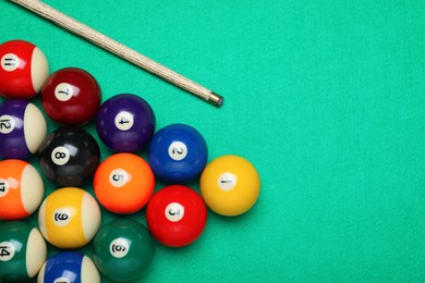 Photo of Set of billiard balls and cue on green table, flat lay. Space for text