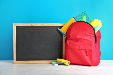 Photo of Small chalkboard and backpack with different school stationery on table