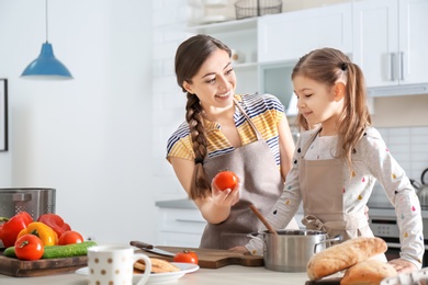 Photo of Young nanny with cute little girl cooking together in kitchen