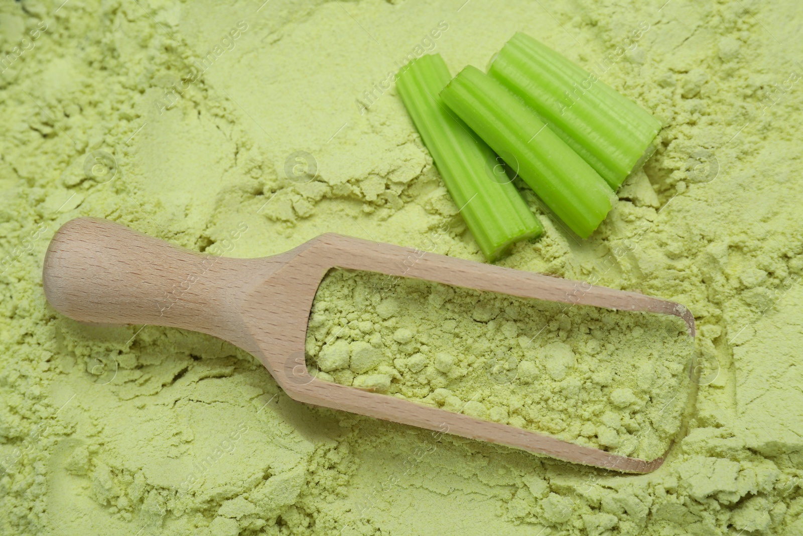 Photo of Natural celery powder, fresh stalks and wooden scoop, above view
