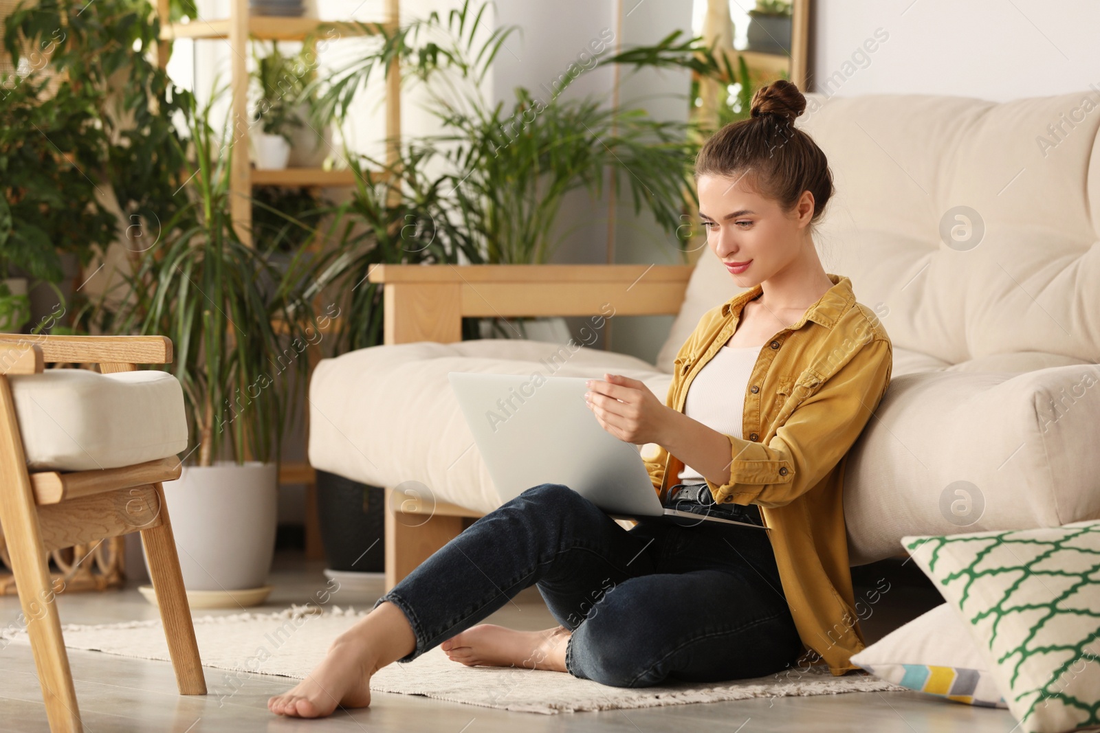 Photo of Happy young woman with laptop in living room