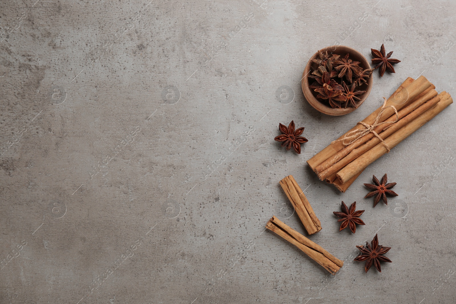 Photo of Aromatic cinnamon sticks and anise on grey table, flat lay. Space for text