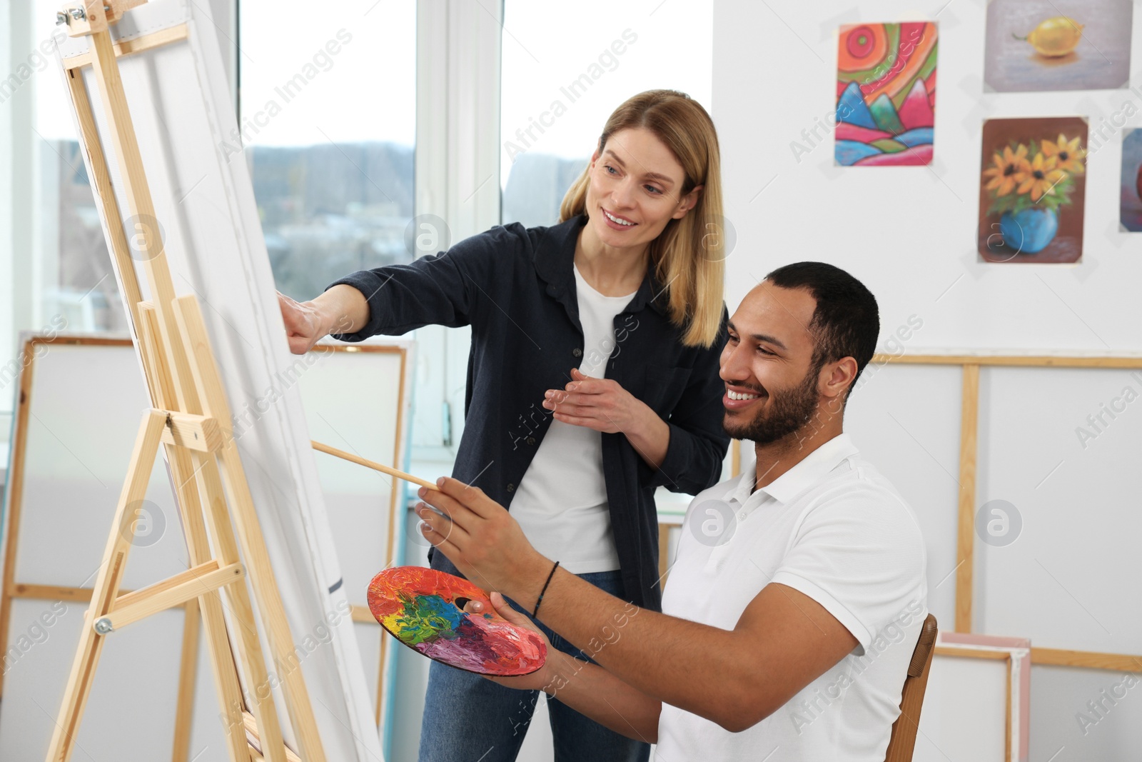 Photo of Artist teaching her student to paint in studio. Creative hobby