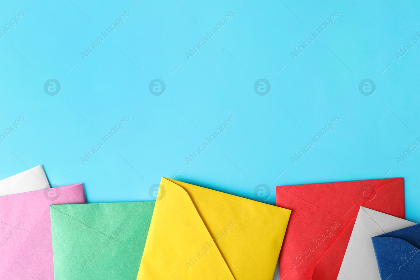 Photo of Colorful paper envelopes on light blue background, flat lay. Space for text