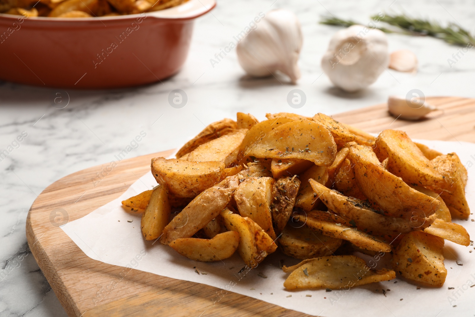 Photo of Board with delicious oven baked potatoes on table, closeup