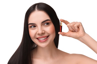 Beautiful young woman holding skincare ampoule on white background